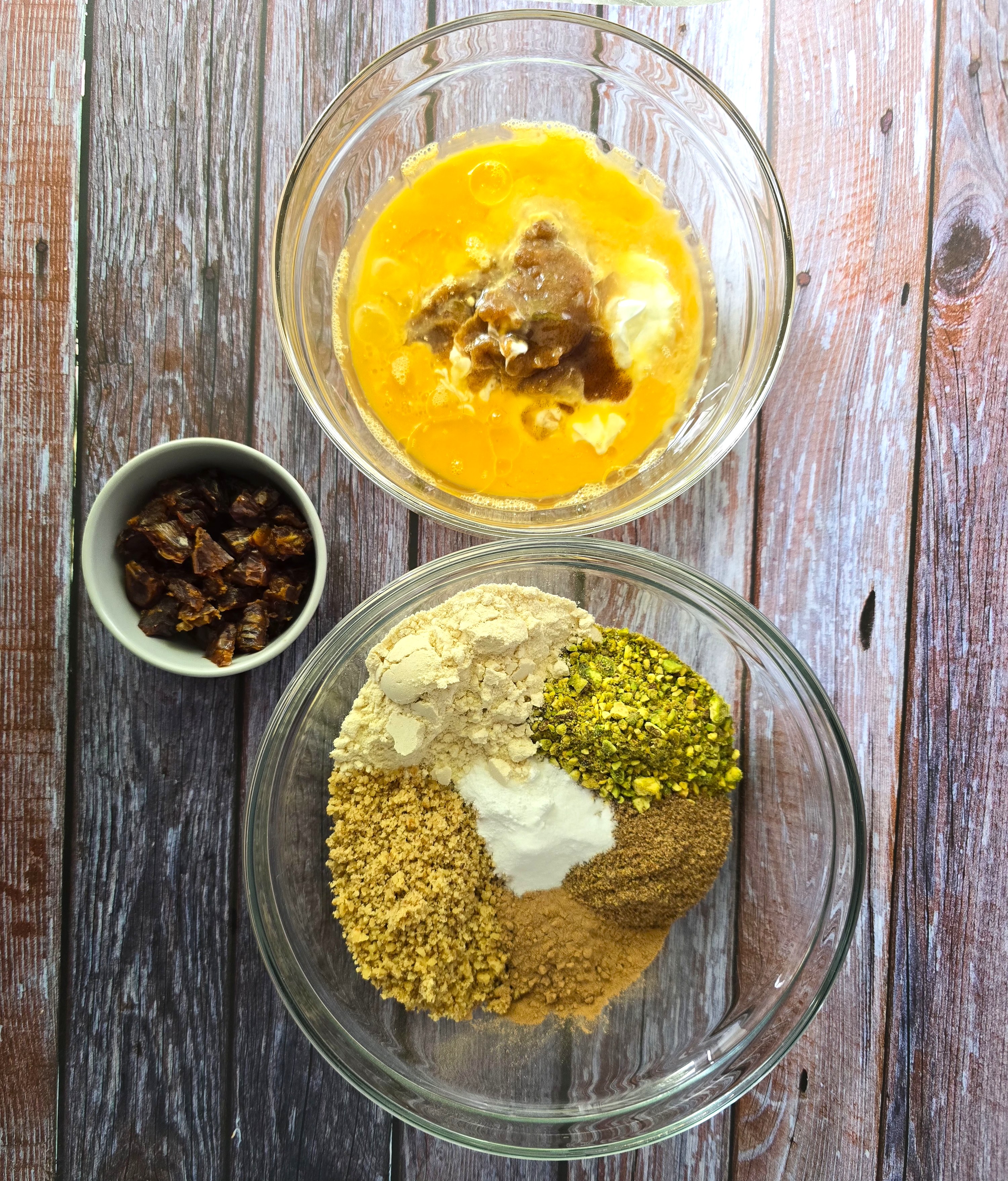 Ingredients for gluten-free pistachio walnut cake - ground walnuts, pistachio, flaxseeds, defatted flour, carob powder, baking powder, baking soda, coconut oil, eggs, lemon juice, chopped dates.