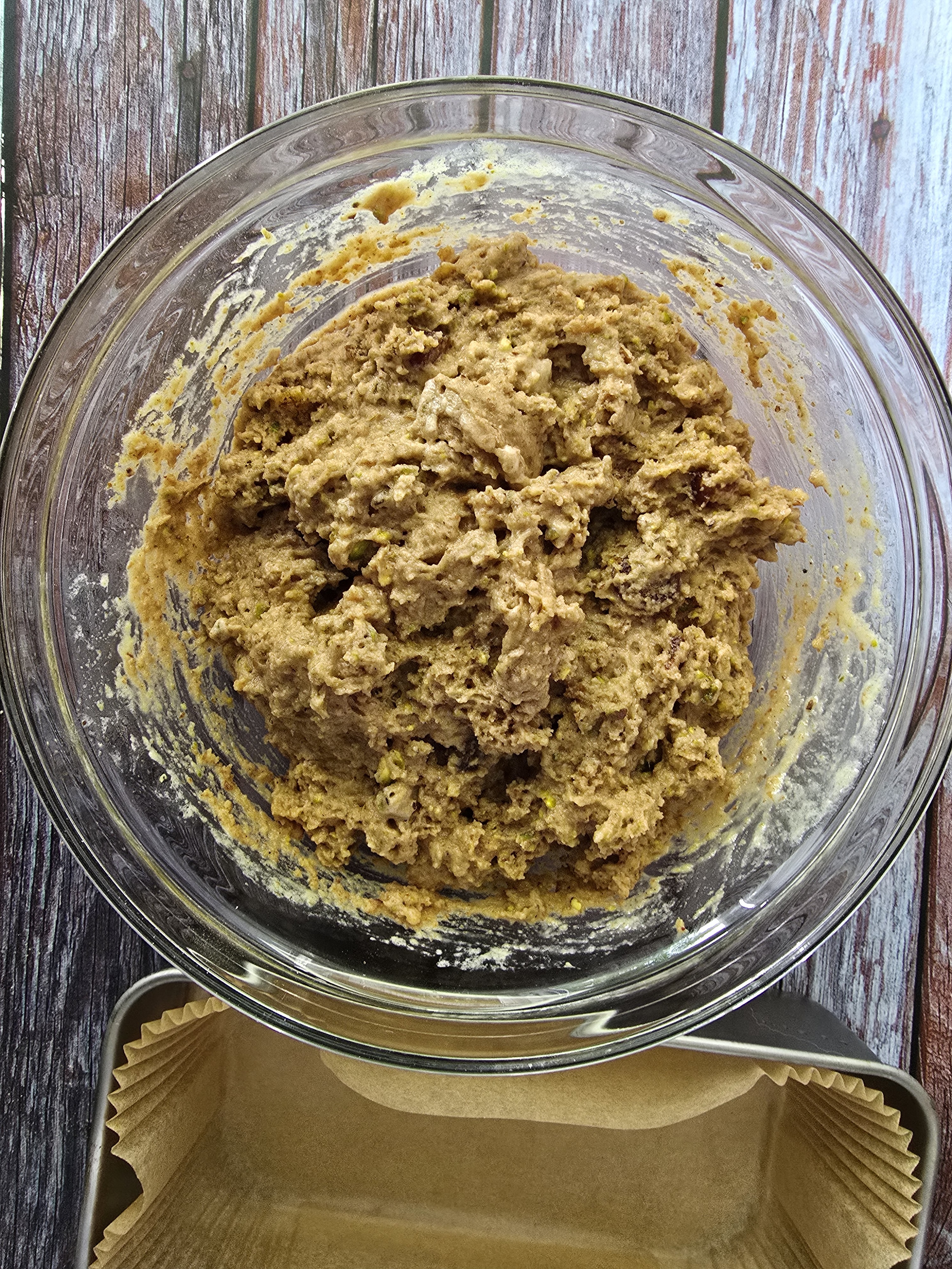 Mixed ingredients for gluten-free pistachio walnut cake - ground walnuts, pistachio, flaxseeds, defatted flour, carob powder, baking powder, baking soda, coconut oil, eggs, lemon juice, chopped dates.