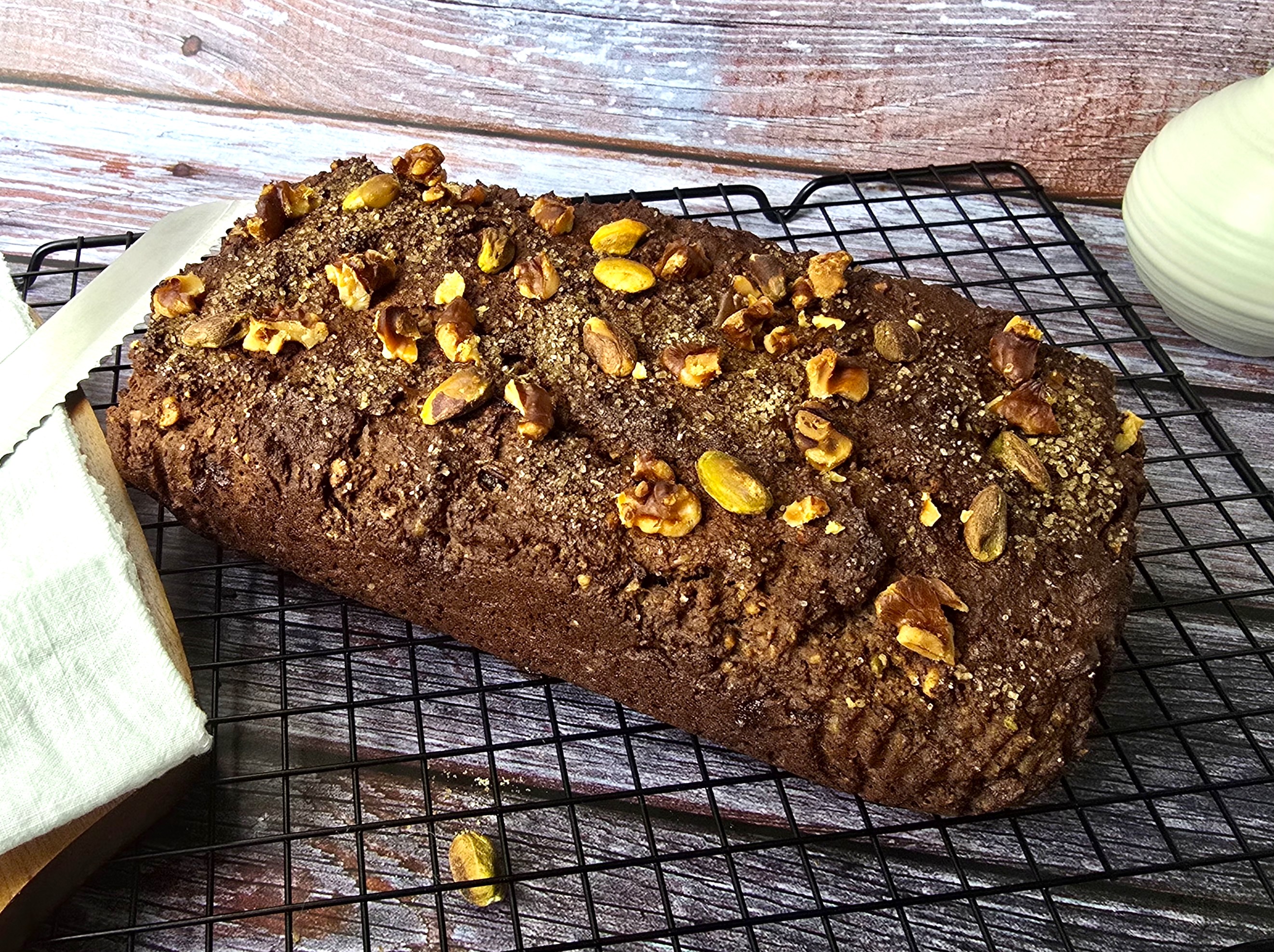 Baked date-sweetened nut cake with pistachio and walnuts on a cooling rack.