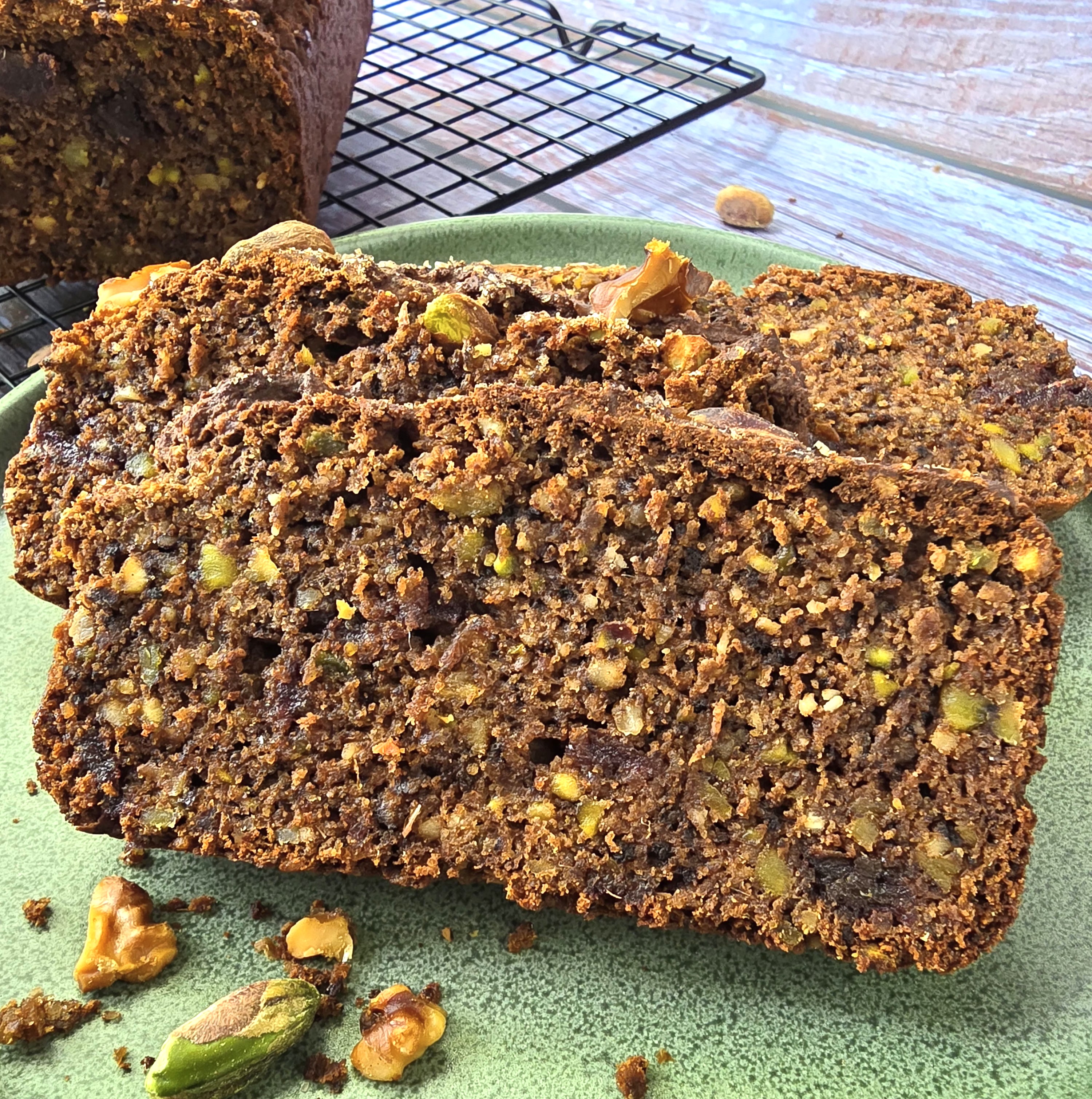 Moist gluten-free pistachio walnut cake sweetened with date paste, sliced on a rustic plate.