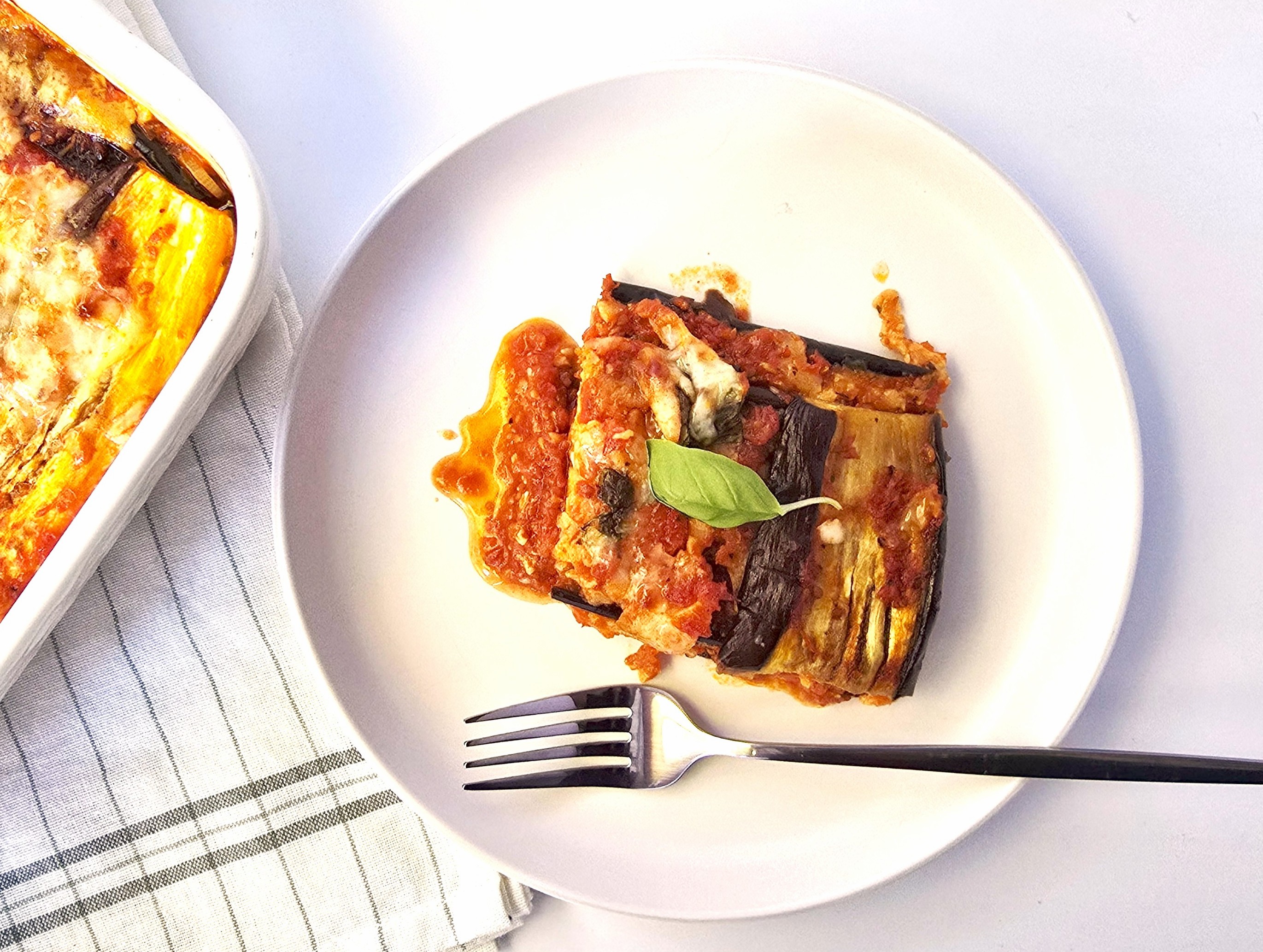 A piece of aubergine parmigiana in a white plate