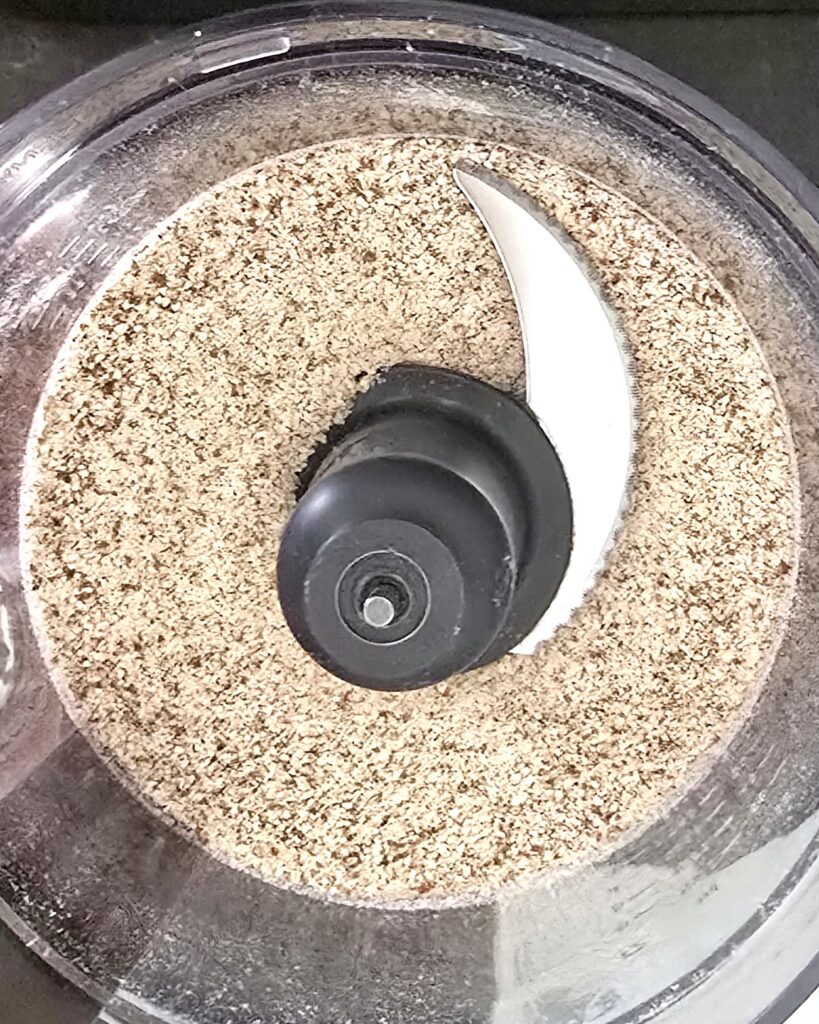 A food processor container with blended dried almond pulp