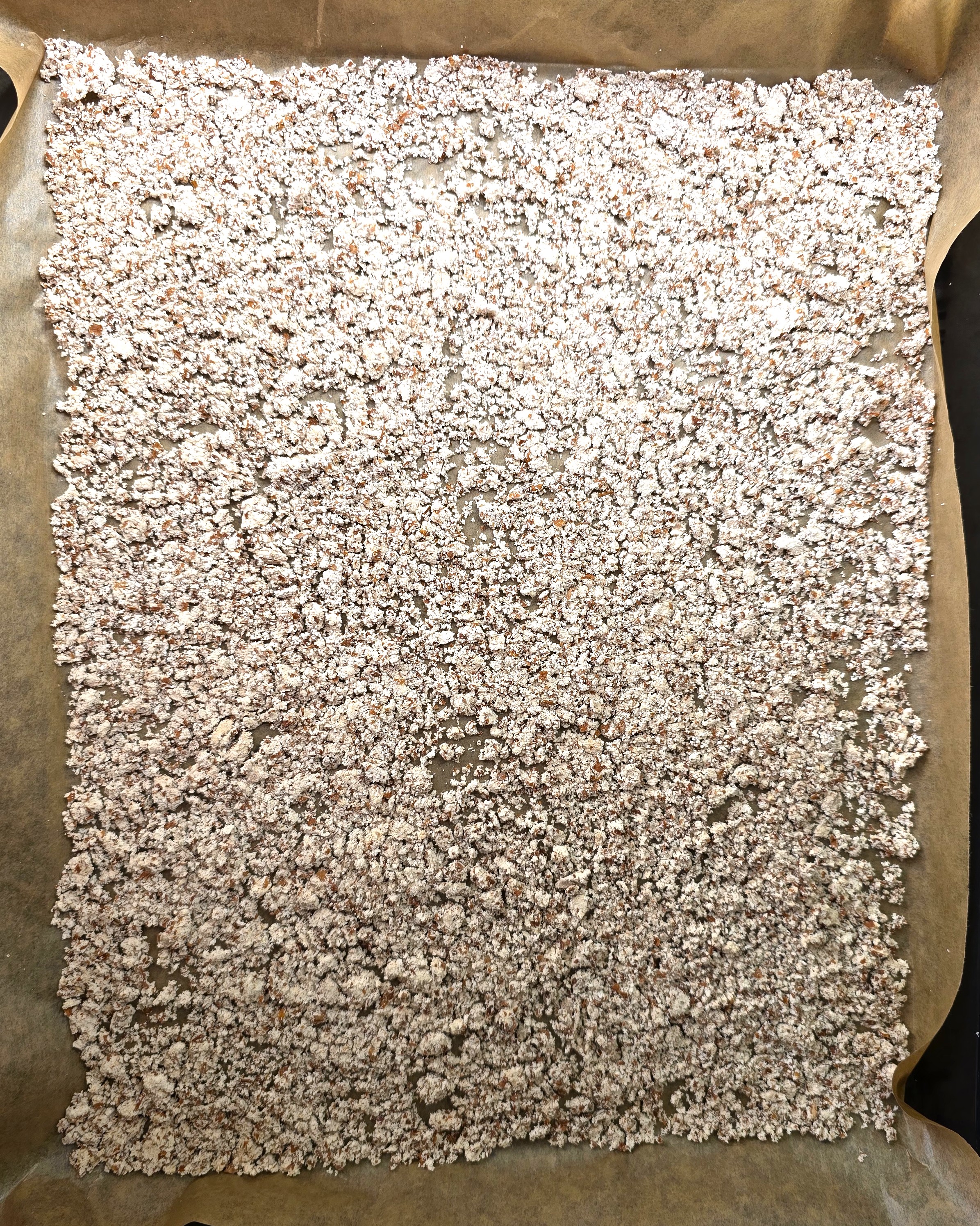 a baking tray with parchment paper and spread dry almond pulp