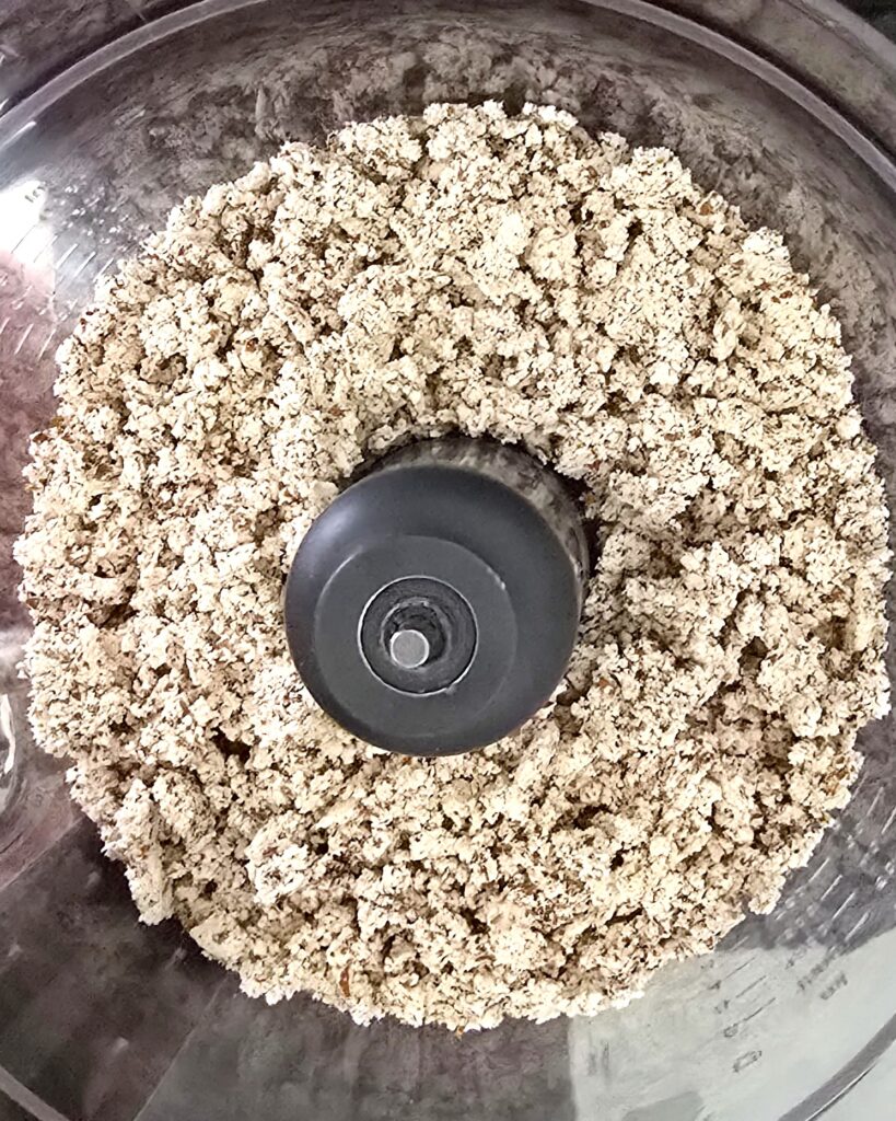 dried almond pulp in a food processor, ready for blending