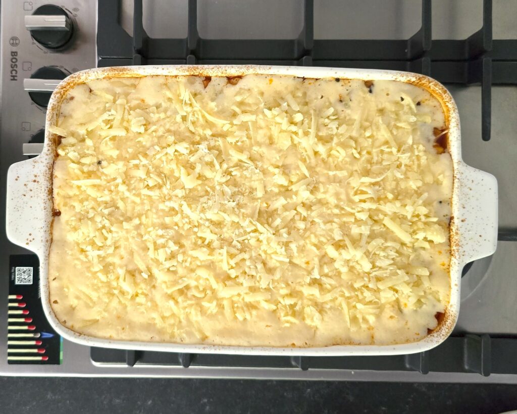 a baking dish with moussaka covered with toppings, ready for final baking
