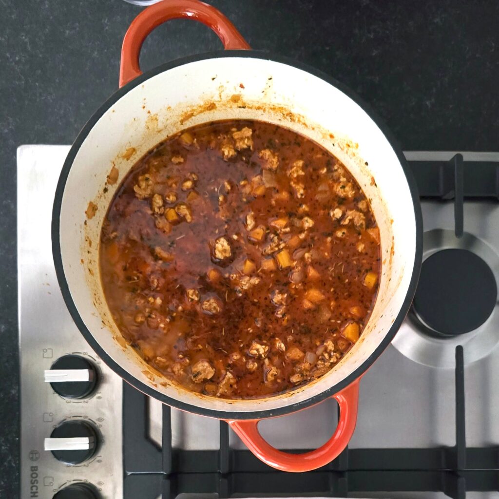 a pot with simmering vegetables and minced meat in cooking moussaka