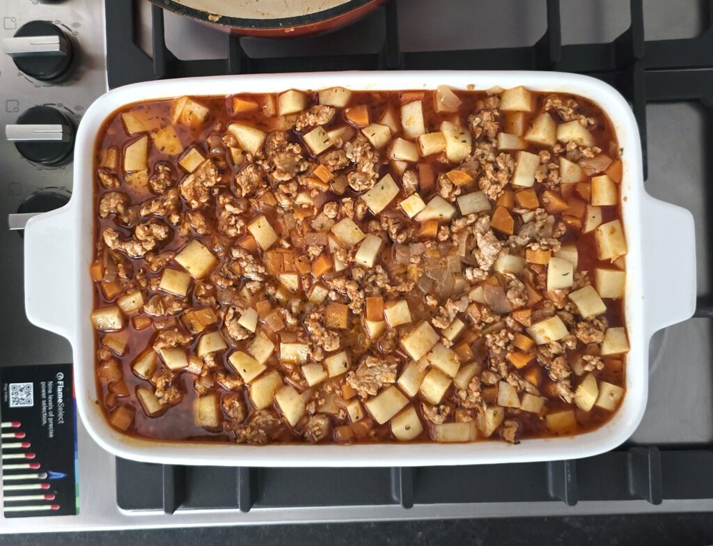 a baking dish with a semi raw moussaka, ready for baking