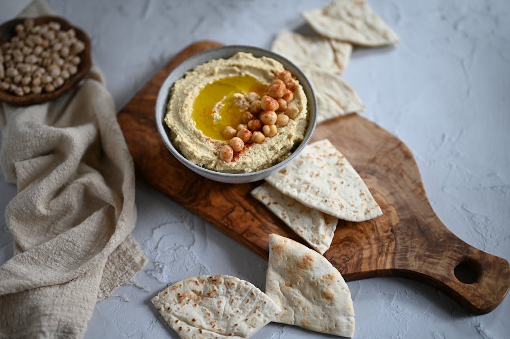 Bowl of creamy hummus with chickpeas and olive oil, served with gluten-free flatbreads – Middle Eastern flavours for gut health