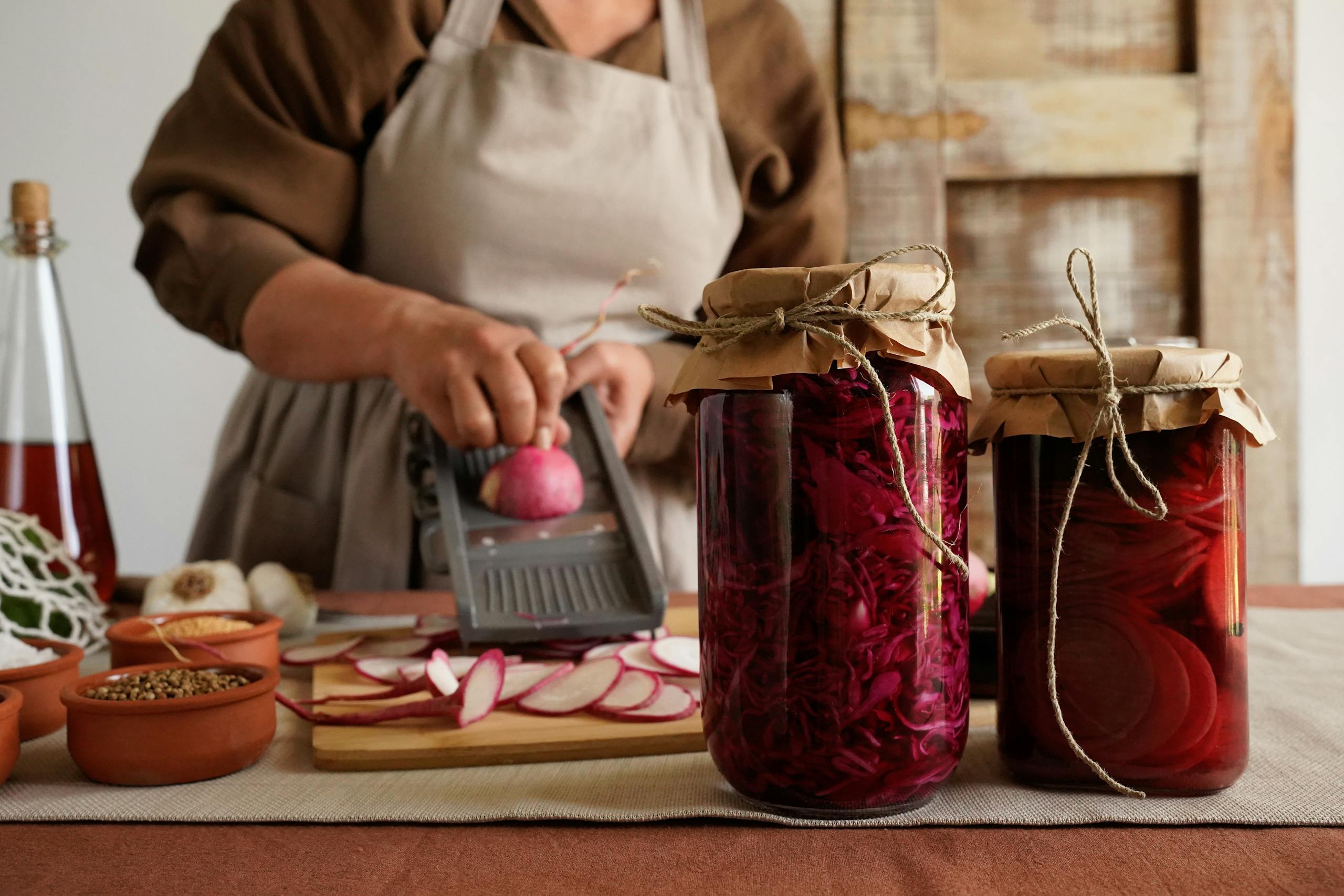 Woman preparing pickled radishes in a rustic kitchen. Ideal for culinary and DIY themes.